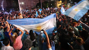 An Argentinian crowd waving flags in celebration of Milei's election.