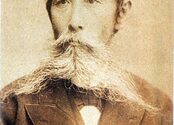 A sepia-toned photograph of Itagaki Taisuke, an older man with a large white beard. 
