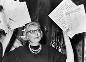 Jane Jacobs holds up handfuls of documents.