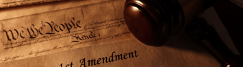 Papers reading "1st Amendment" and "We the People" are on a desk along with a gavel.