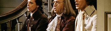 William Daniels as John Adams, Howard De Silva as Benjamin Franklin, and Ken Howard as Thomas Jefferson sit side by side on a staircase, singing.