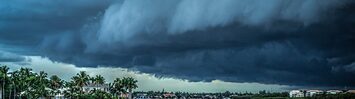 A storm cloud nears the Florida coast as boats sail on the water near homes.